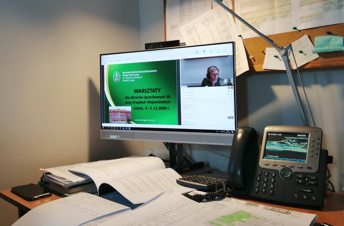 Zdjęcie biurka z dokumentami oraz monitora komputera z warsztatów on-line.