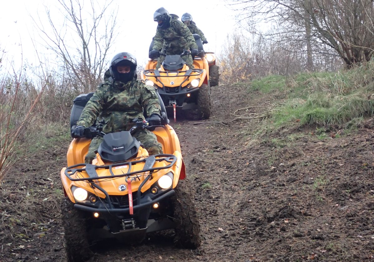 Trzech funkcjonariuszy Straży Granicznej na pojazdach ATV w terenie.