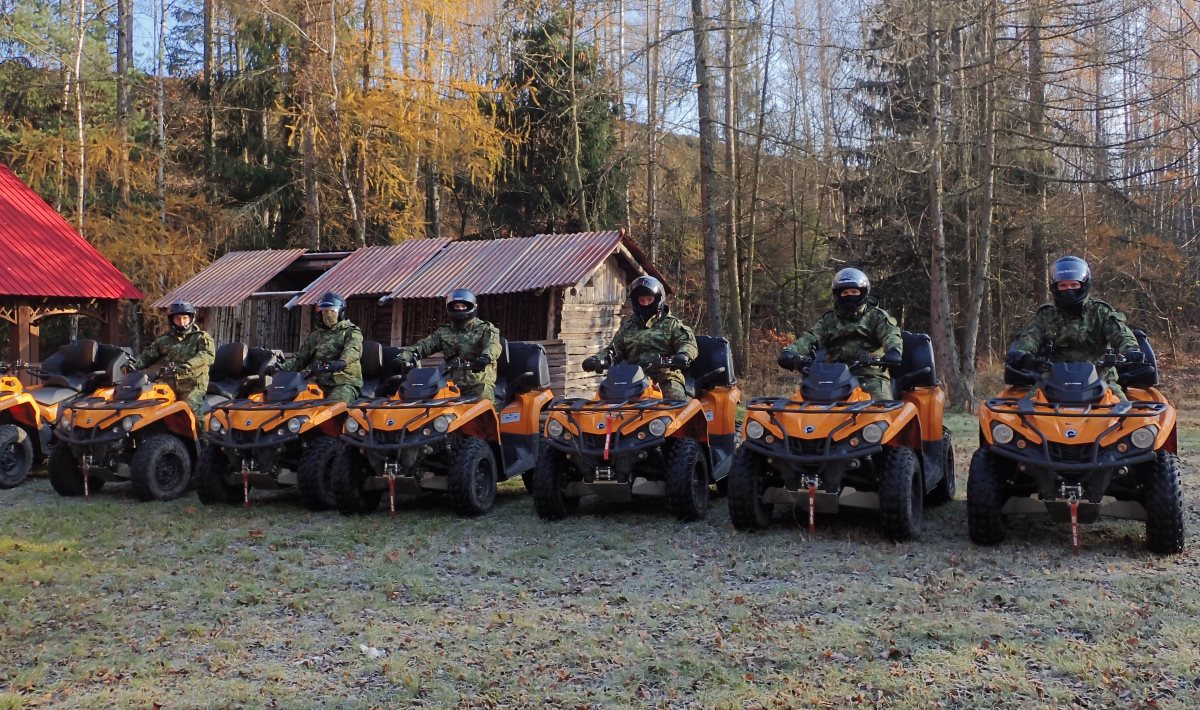 Sześciu funkcjonariuszy Straży Granicznej na pojazdach ATV w terenie leśnym.