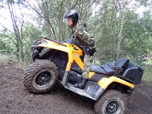  Funkcjonariusz Straży Granicznej na pojeździe ATV w terenie leśnym podczas pokonywania przeszkody.