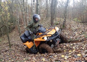  Funkcjonariusz Straży Granicznej na pojeździe ATV w terenie leśnym podczas pokonywania przeszkody.