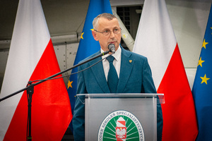Starosta Powiatu Lubańskiego podczas przemowy, w tle flagi Polski i Unii Europejskiej