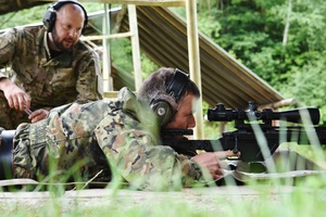 Funkcjonariusz SG podczas treningu strzeleckiego. W tle instruktor