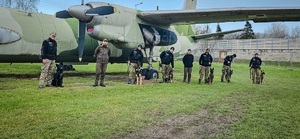 Zdjęcie grupowe funkcjonariuszy SG z psami służbowymi. W tle samolot Zdjęcie grupowe funkcjonariuszy SG z psami służbowymi. W tle samolot