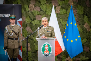 Pani gen. bryg. SG Wioleta Gorzkowska, stojąca przy mównicy, w tle flagi Polski i UE