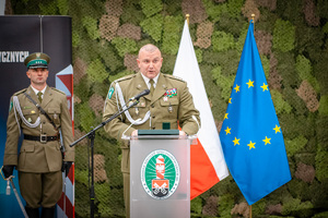 Komendant Centrum Szkolenia SG stojący przy mównicy, w tle flaga Polski i UE