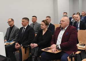 Grupa uczestników warsztatów siedzących na krzesłach w sali wykładowej Grupa uczestników warsztatów siedzących na krzesłach w sali wykładowej