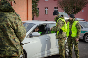 Słuchacze szkolenia w zakresie szkoły podoficerskiej podczas egzaminu praktycznego - kontrola  dokumentów w ruchu drogowym. W tle pojazd służbowy i pojazd nieoznaczony. Słuchacze szkolenia w zakresie szkoły podoficerskiej podczas egzaminu praktycznego - kontrola  dokumentów w ruchu drogowym. W tle pojazd służbowy i pojazd nieoznaczony.