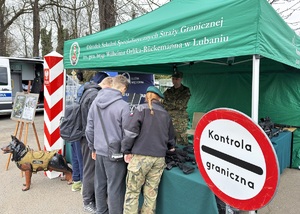 Uczniowie przy stoisku promocyjnym SG Uczniowie stoją przy stoisku SG. Pod namiotem stoi funkcjonariusz SG